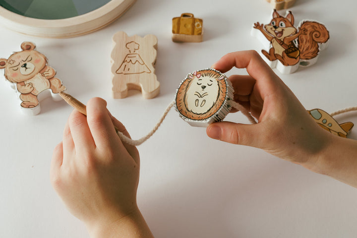 A child threads Hazel onto a cord, with Calm Crew puzzle pieces and an engraved volcano strategy symbol beside their hands.